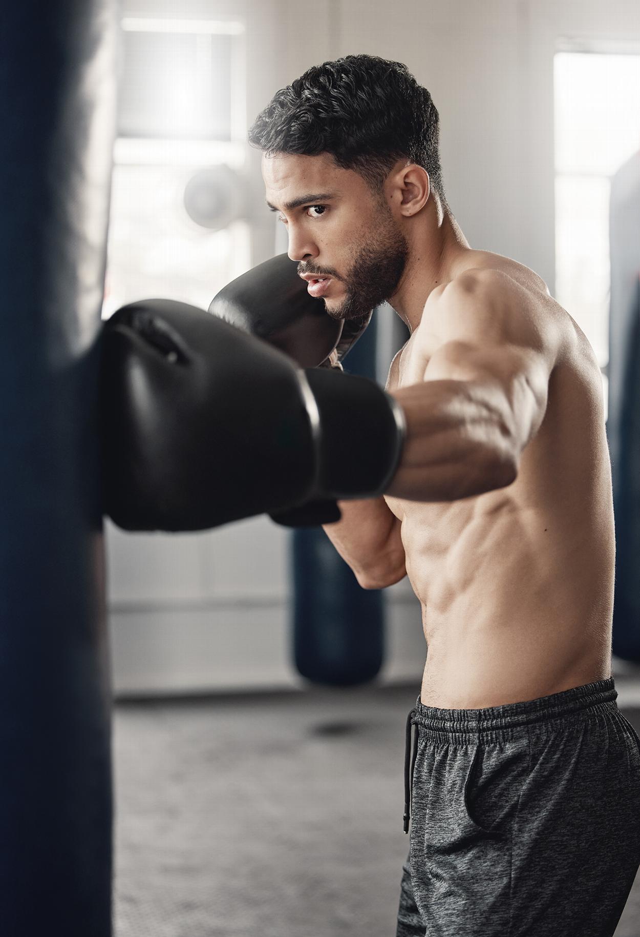 Man boxing punching bag at gym