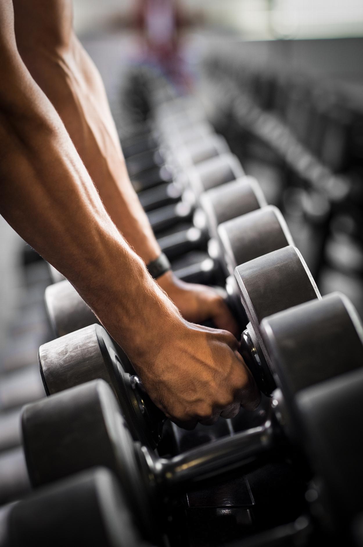 Man picking up weights from rack at gym