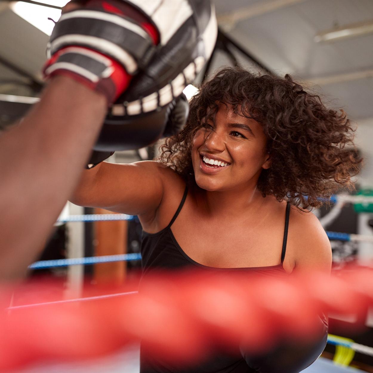 Woman boxing with coach at gym